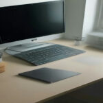 A clean modern home workspace setup featuring a laptop displaying web guidelines next to a notebook.