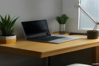 A modern minimalist desk with a laptop and credit card on a wooden surface in daylight.