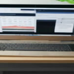 A clean modern workspace with a laptop open to digital seller account settings and registration controls.