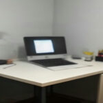 A minimalist workspace setup featuring a laptop and notebook used for remote AI-assisted freelancing and digital tasks.