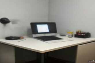 A minimalist workspace setup featuring a laptop and notebook used for remote AI-assisted freelancing and digital tasks.