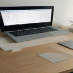Minimalist home office desk with a modern laptop displaying freelance financial planning tools and project metrics.