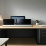 Minimalist home office setup with a computer screen showing digital art files prepared for an online storefront.