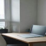 A modern minimalist home office workspace with a open laptop sitting on a wooden desk.