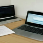 A modern laptop and financial notes on a clean wooden desk representing Amazon KDP ad cost analysis.