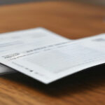 A smartphone lying next to grocery receipts on a wooden desk demonstrating digital receipt scanning safety.
