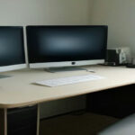 Clean home office desk with a computer monitor and phone headset set up for remote call center work.