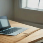A modern laptop and smartphone displaying bandwidth monitoring software on a clean home office desk.