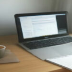 Laptop setup with studio headphones on a home office desk prepared for digital transcription work.