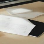 A modern freelance workspace featuring a laptop with project management software and clear daylight on a wooden desk.